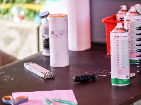 Werkzeugtisch mit Maulschlüssel, Schraubendreher, Maßstab, Sprühdosen, Papierrolle und Schraubenfeder.