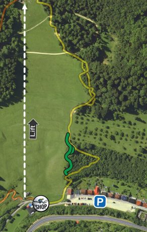 Parkplatz und Shop am unteren Rand, Weg verläuft durch grüne Wiesen und Wald zu einem Ziel. Pfeil weist nach oben.