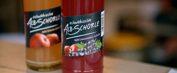 Zwei Flaschen Alb-Schorle, eine Apfel, eine Apfel-Johannisbeer, mit Obstabbildungen auf dem Etikett.