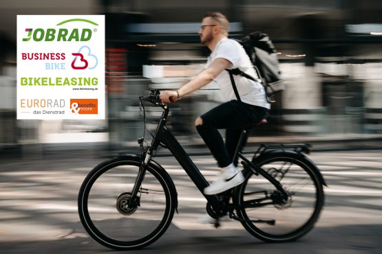 Ein Mann fährt auf einem schwarzen E-Bike, trägt einen Rucksack und ist in Bewegung; im Hintergrund sind verschwommene Gebäude.